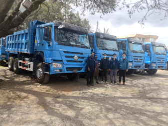 A group photo commemorates 60 dump trucks for the Ehiopian Ministry of Defense undergoing pre-delivery inspection